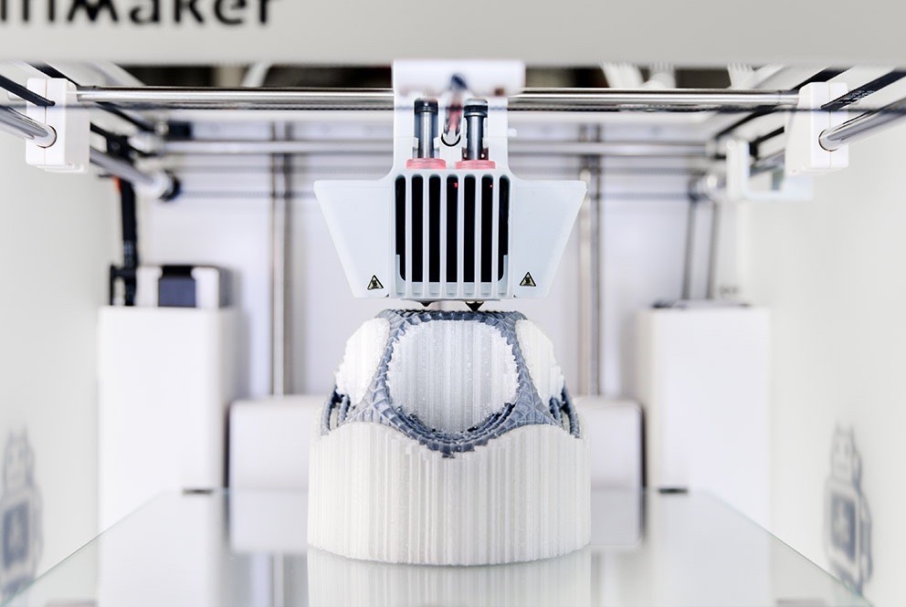 Ultimaker dual-extrusion FDM 3D printer depositing PLA for the model and water-soluble PVA support material during a print.